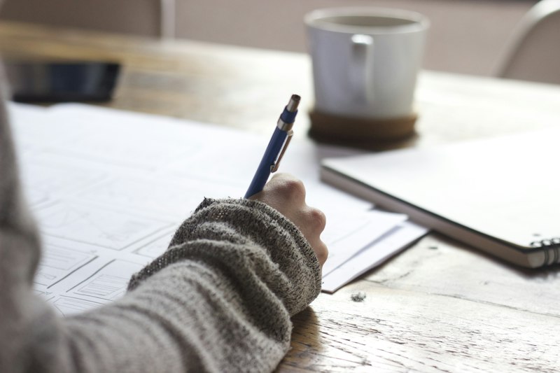 Person writing notes while learning online